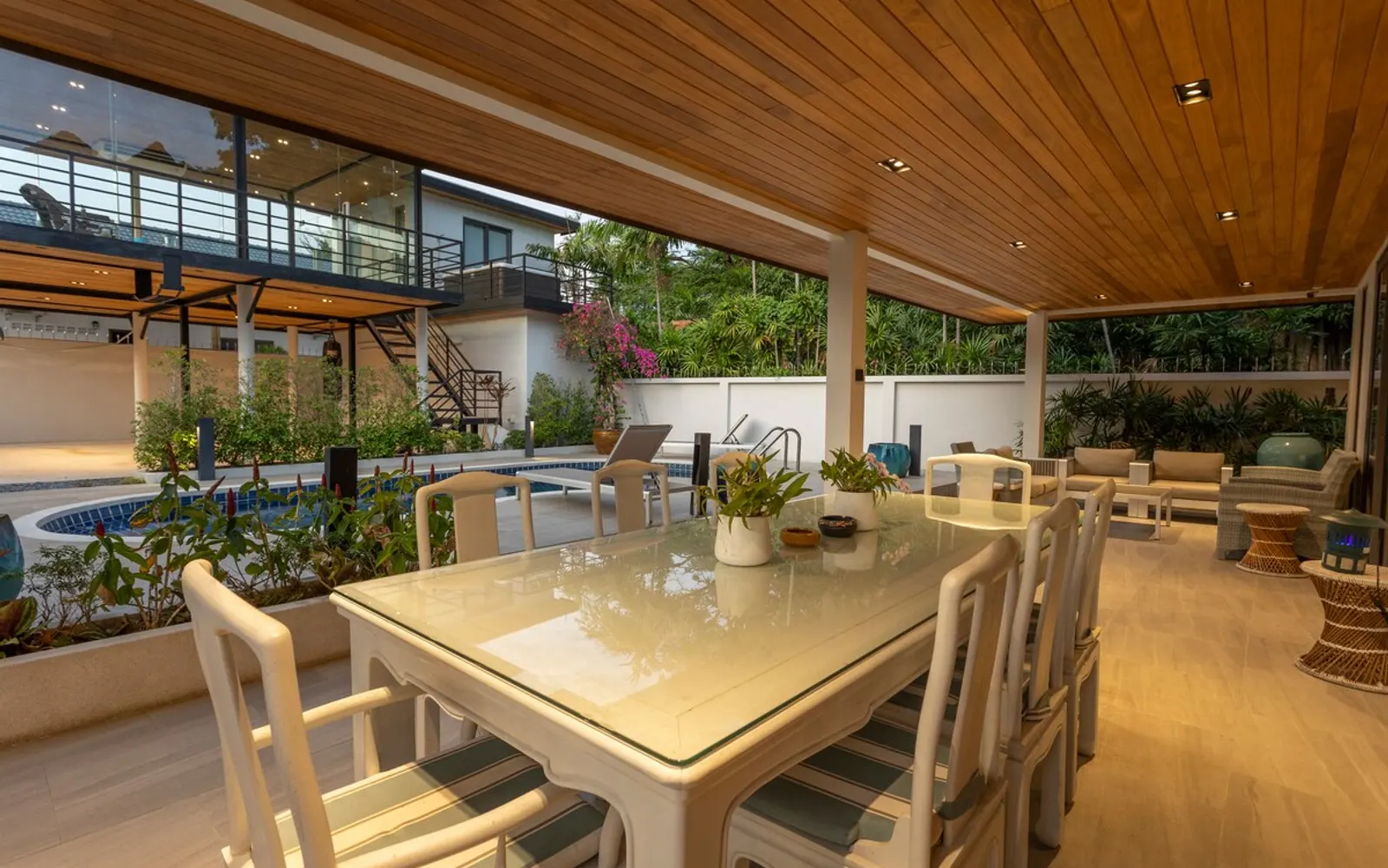 Poolside lounge area of a Rawai villa listed on Golda Trip, framed by tropical plants